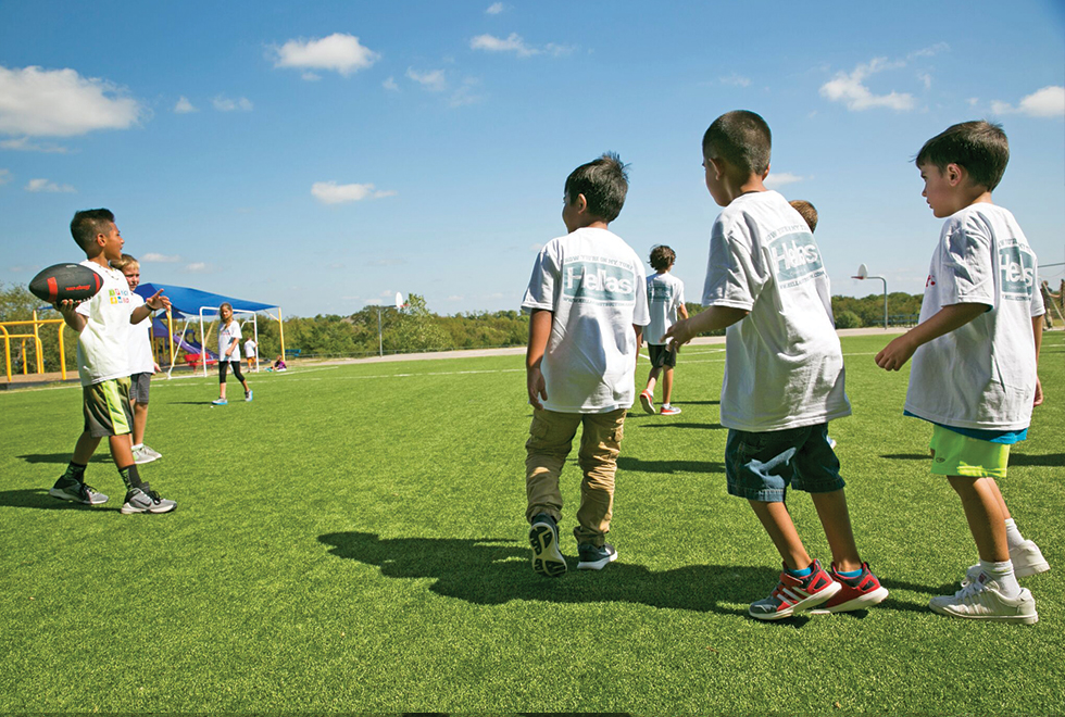 Kids playing football at Sue E. Rattan Elementary on Anna ISD’s new Kickabout field built by Hellas Construction.
